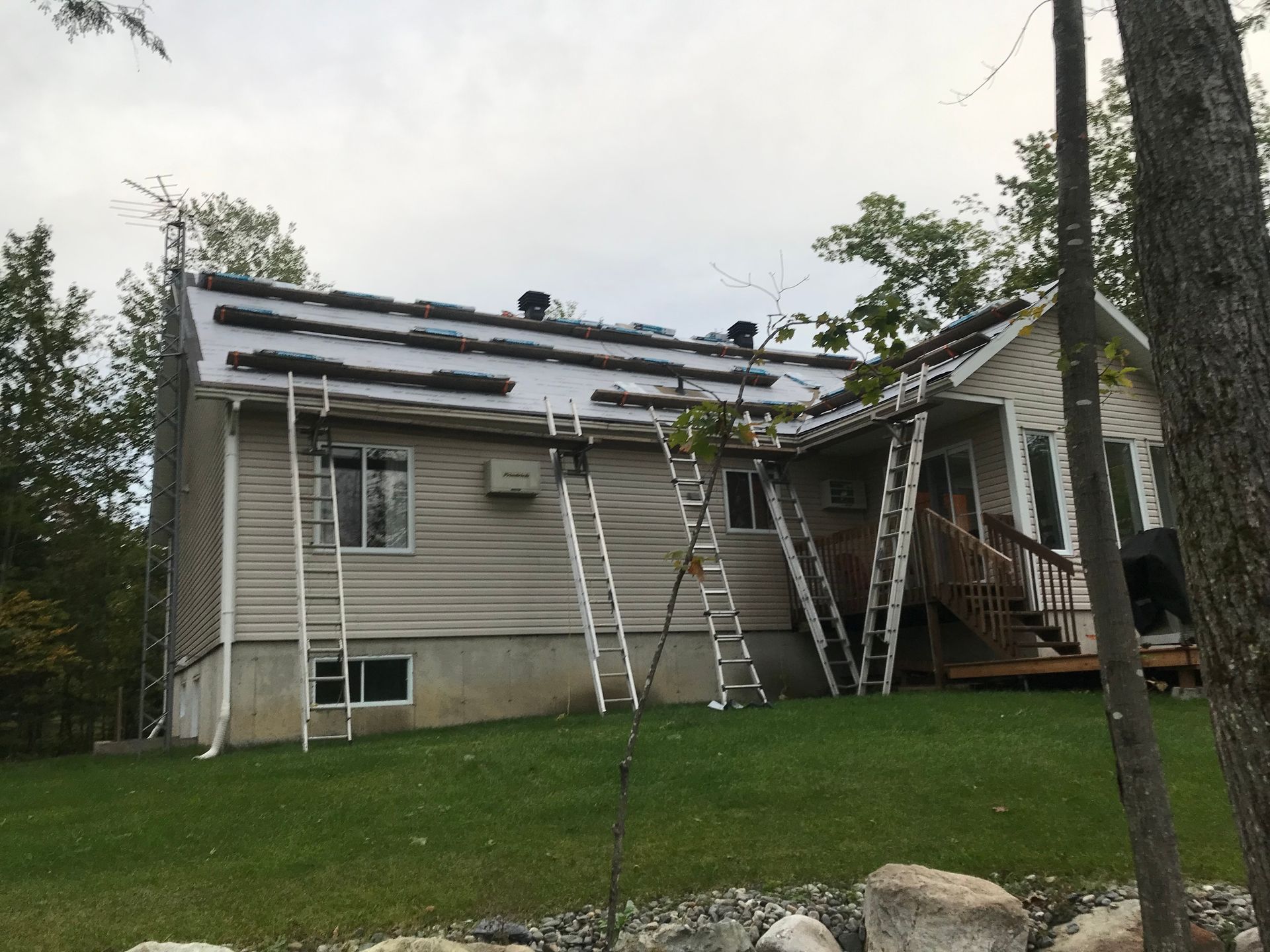 Une maison avec un toit en cours de réparation avec des échelles dessus.