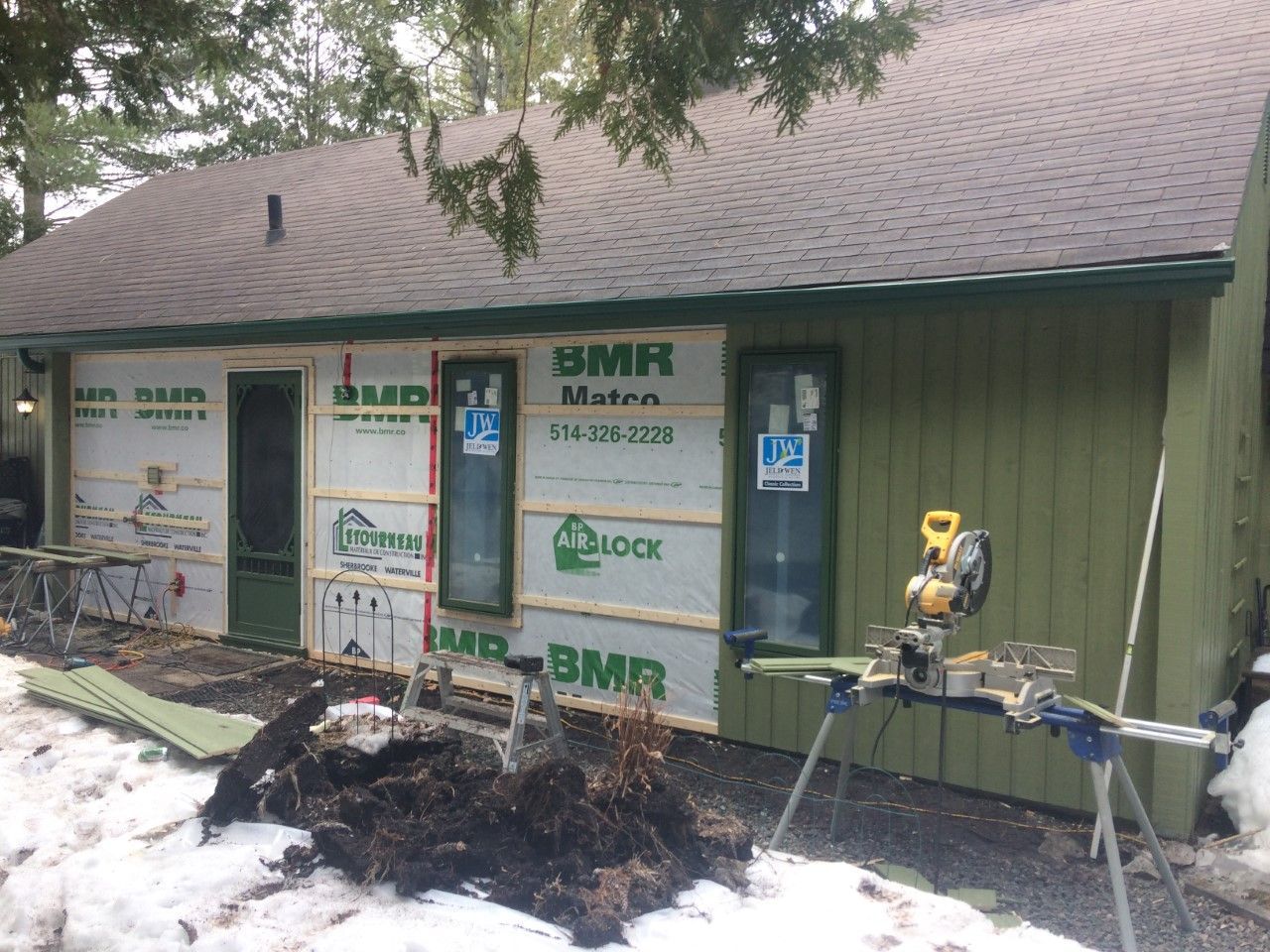 Une maison est en train d'être rénovée dans la neige avec une scie devant elle.