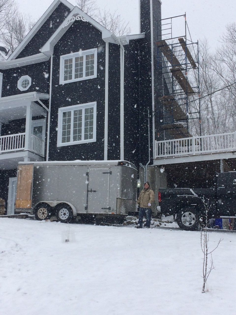 Une remorque est garée devant une maison sous la neige
