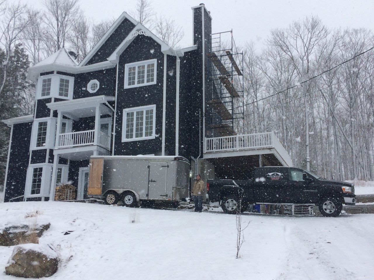 Un camion est garé devant une grande maison sous la neige.