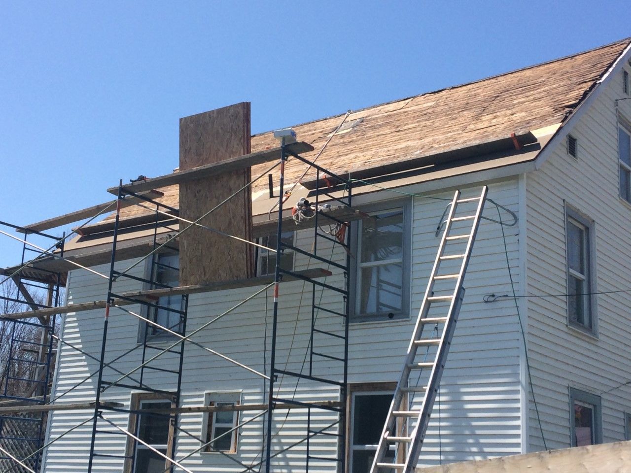 Une maison blanche avec un échafaudage autour et une échelle sur le côté.