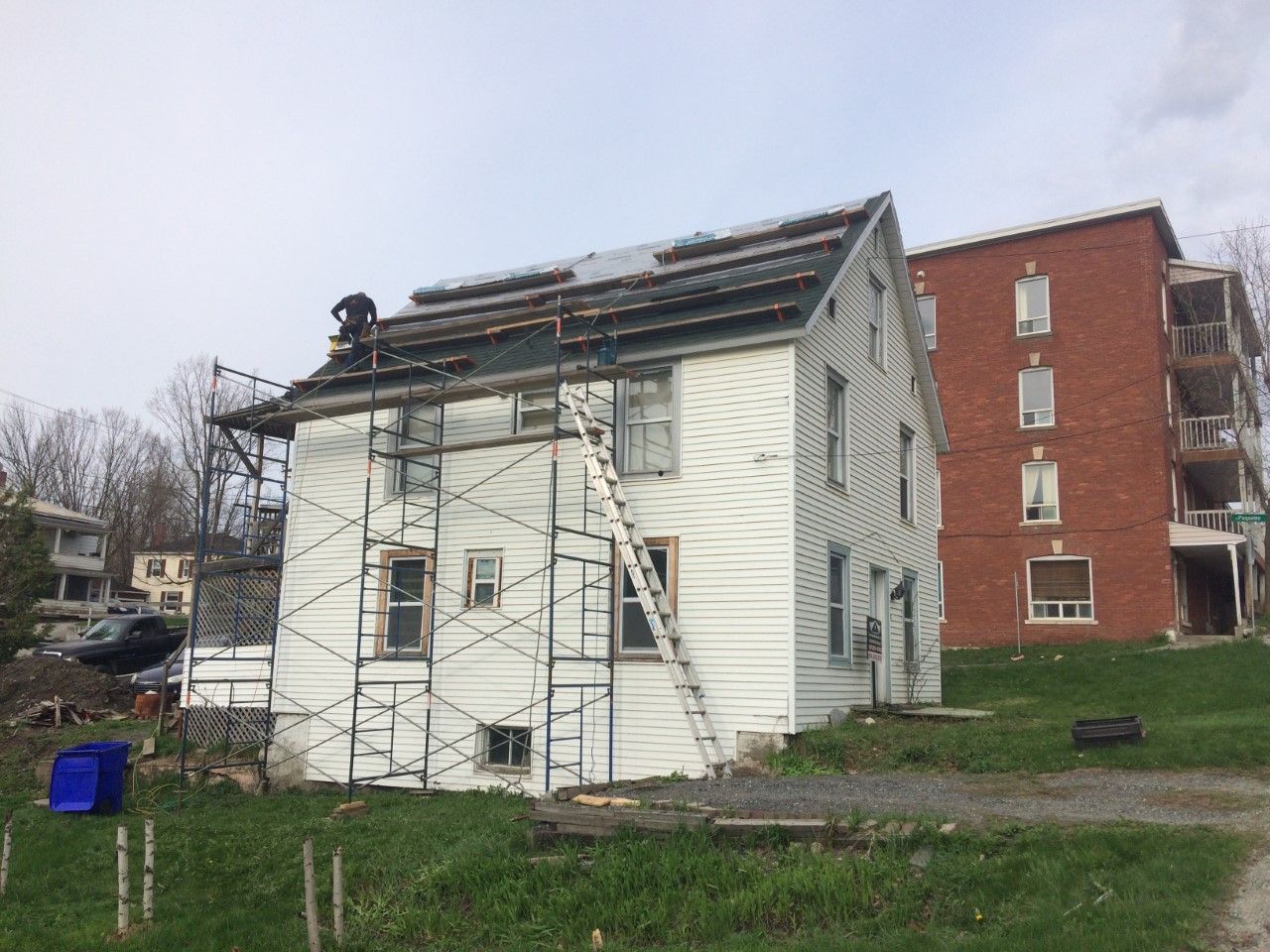 Un homme travaille sur le toit d'une maison blanche.