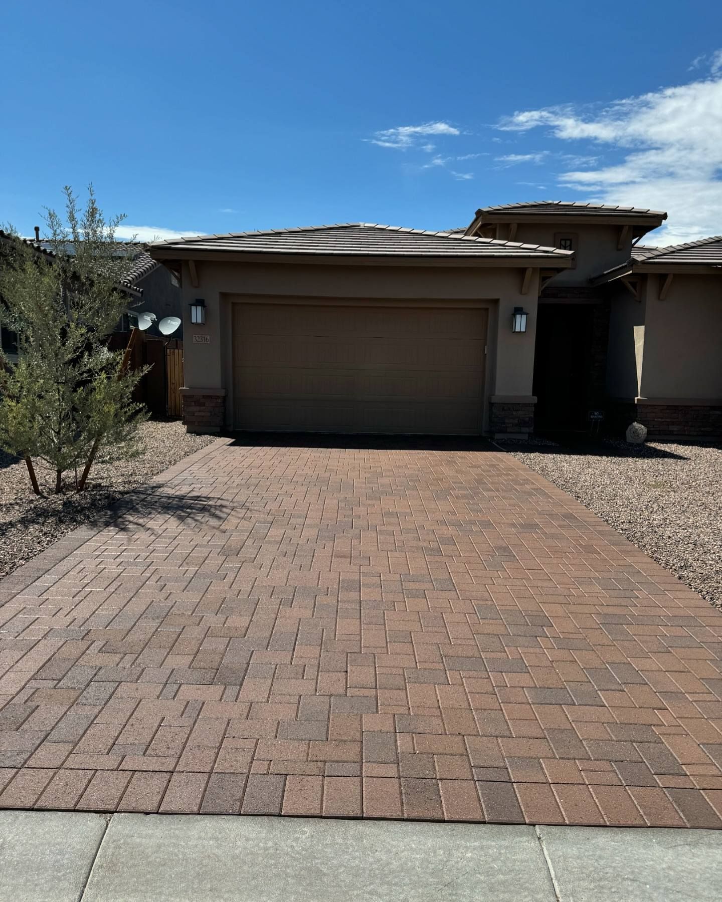 A house with a garage and a brick driveway in front of it.