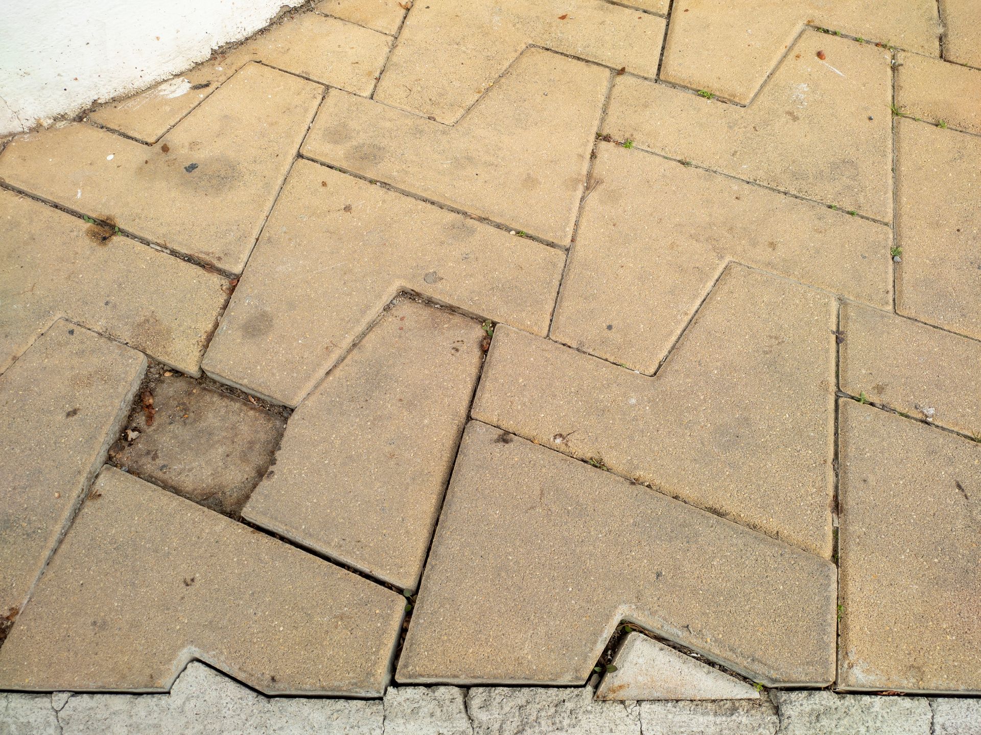 A close up of a broken brick sidewalk with a diagonal pattern.