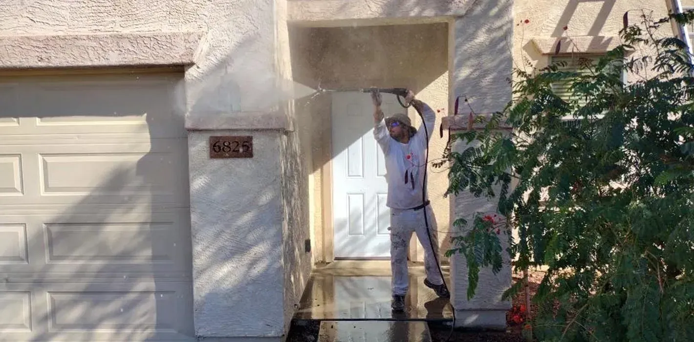 A person is using a high pressure washer to clean a brick walkway.