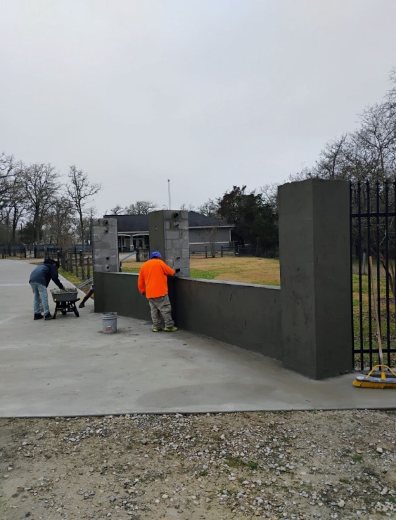 A couple of men are working on a concrete wall.