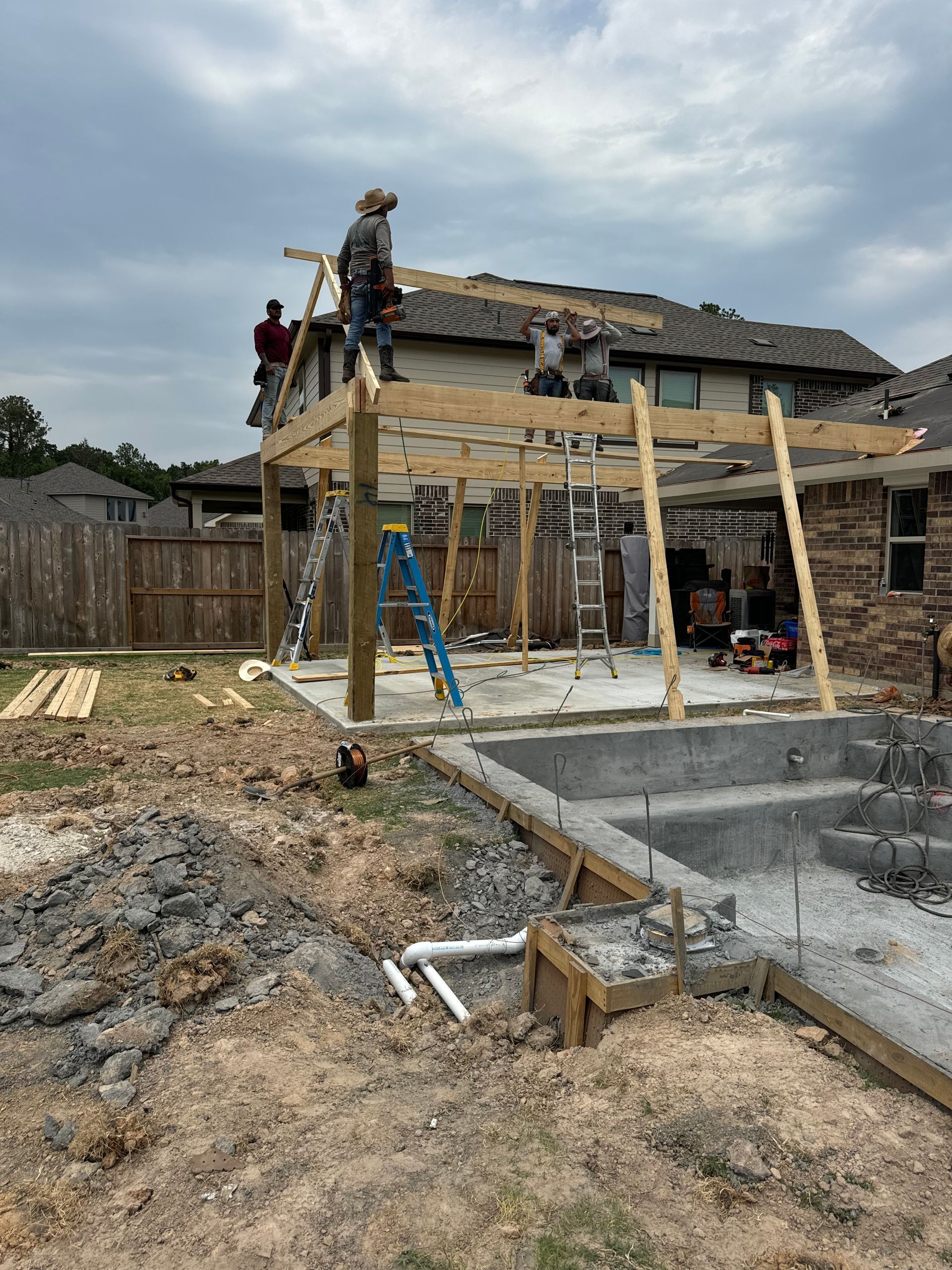 A group of people are working on a wooden structure in front of a house.