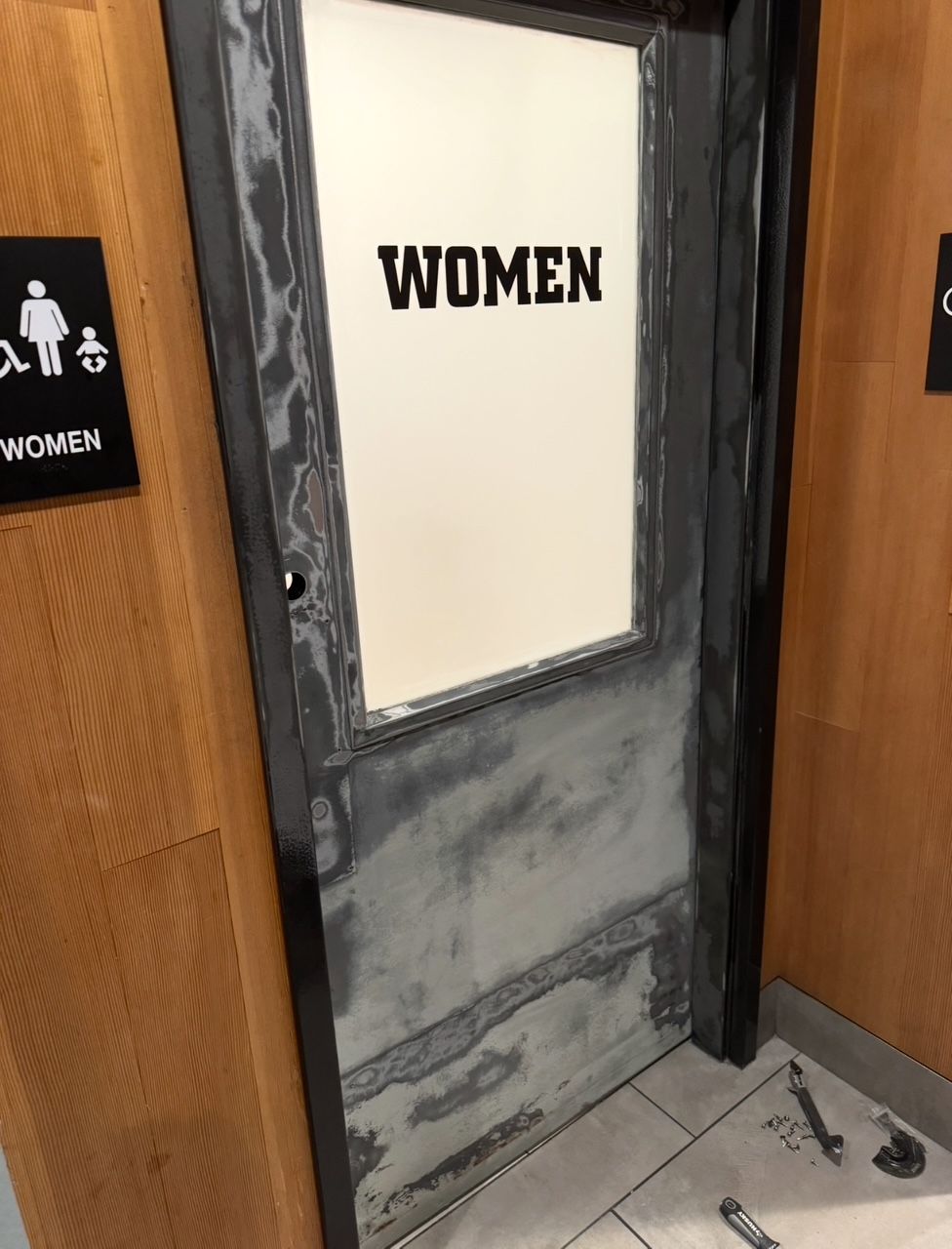 A women 's bathroom door is being painted
