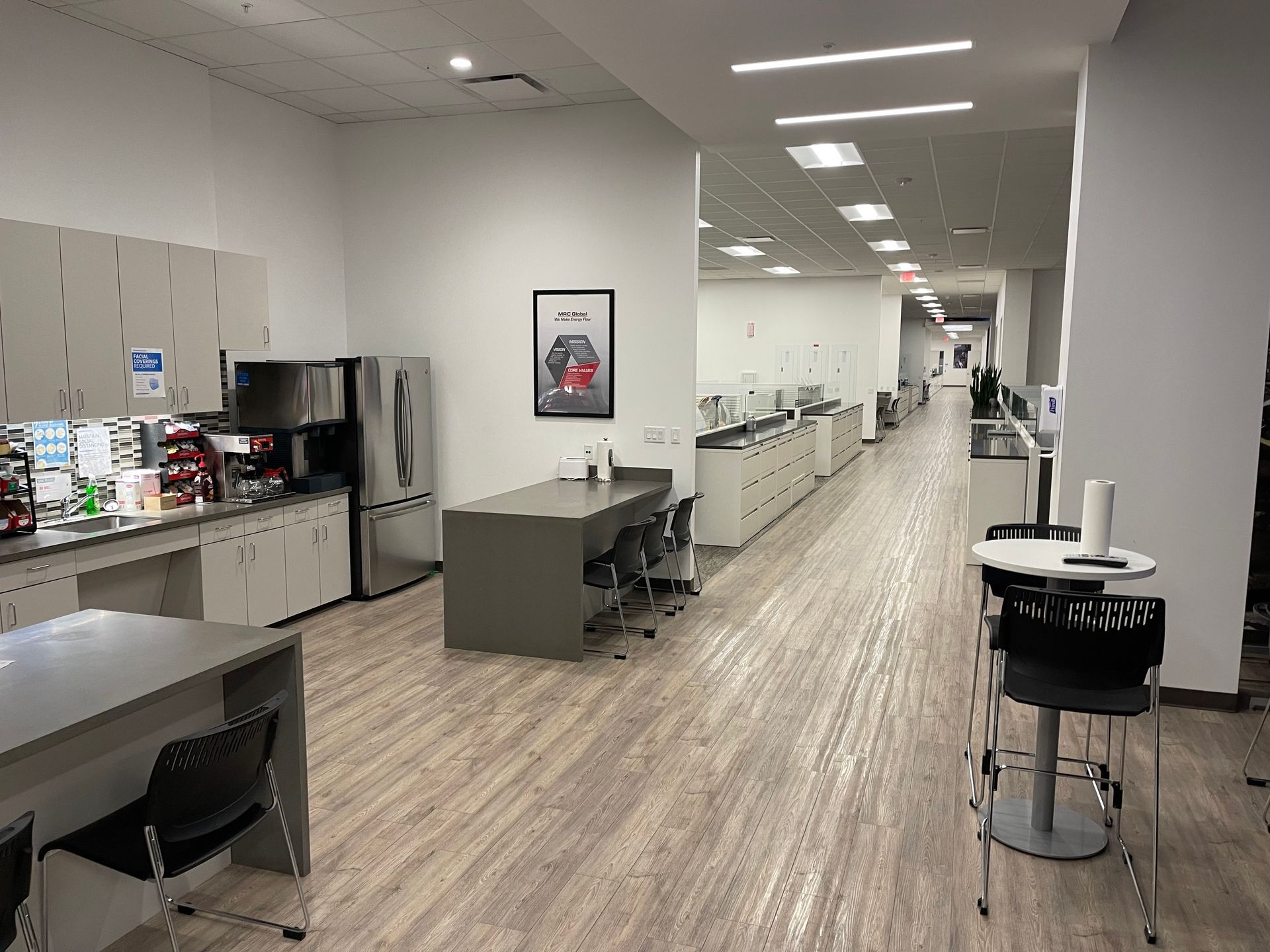 A long hallway with tables and chairs in an office building.