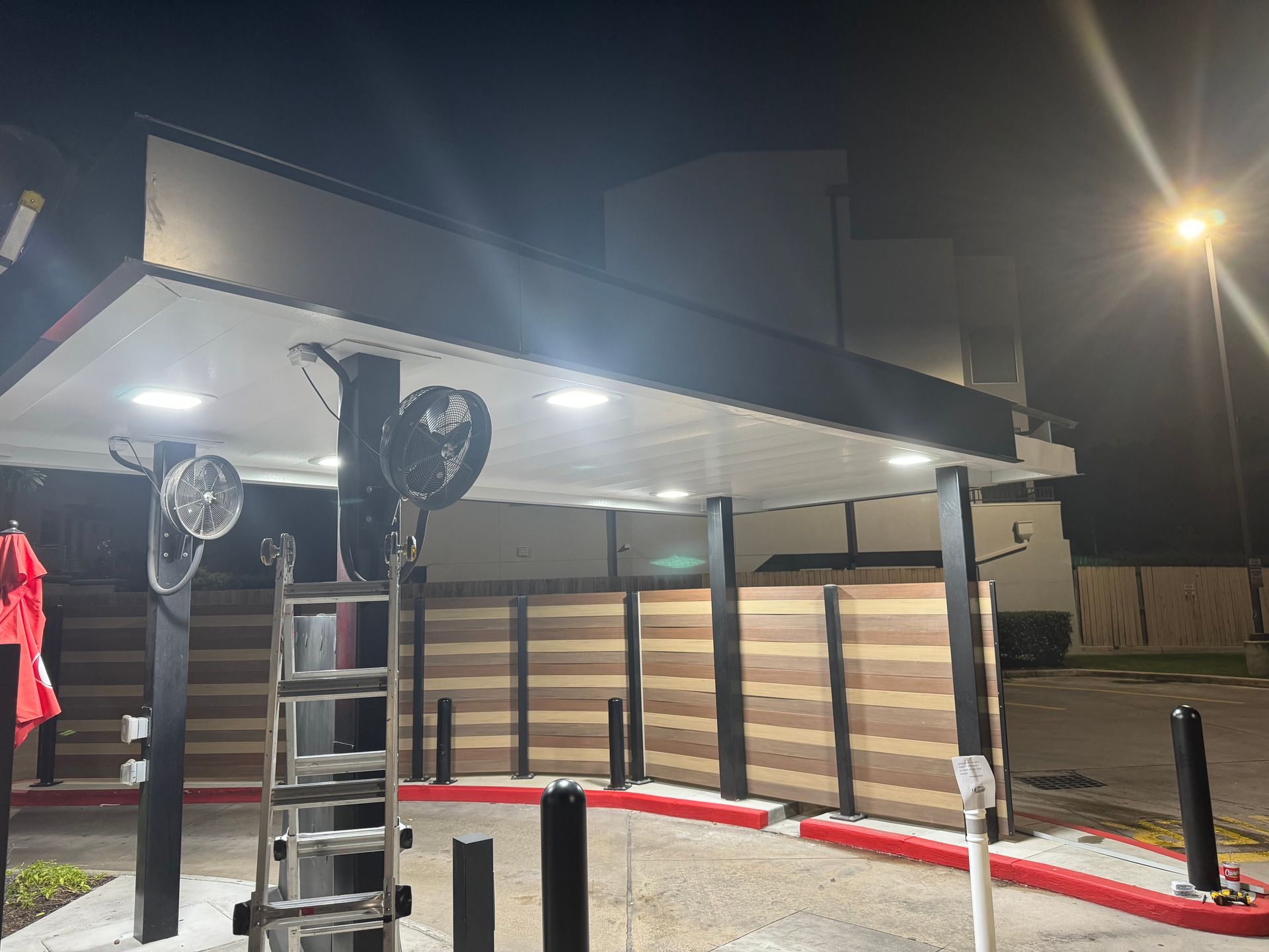A gas station is lit up at night with a red umbrella in front of it.