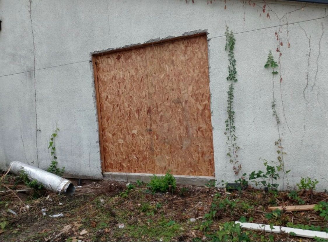 A window on the side of a building is boarded up.