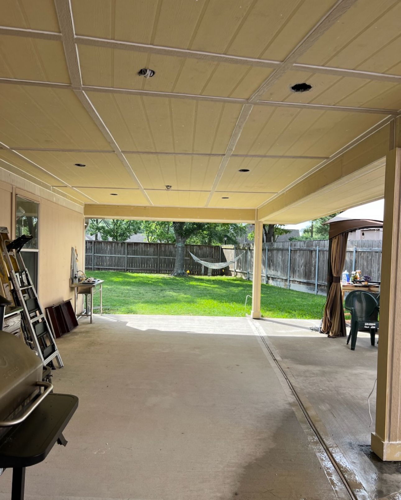 A large covered patio with a hammock and a grill.