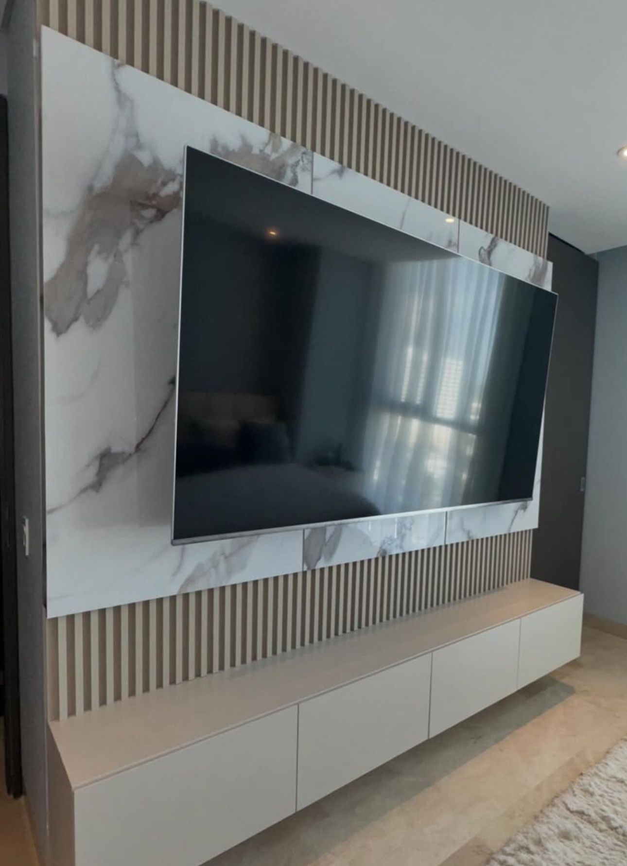 A large flat screen tv is mounted on a wall in a living room.
