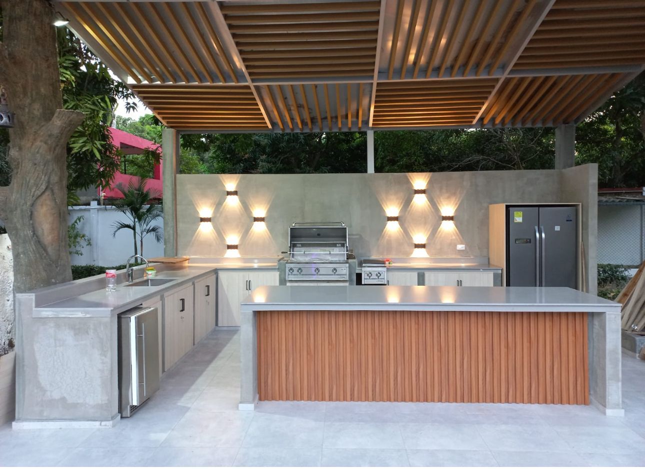 An outdoor kitchen with a grill and a refrigerator