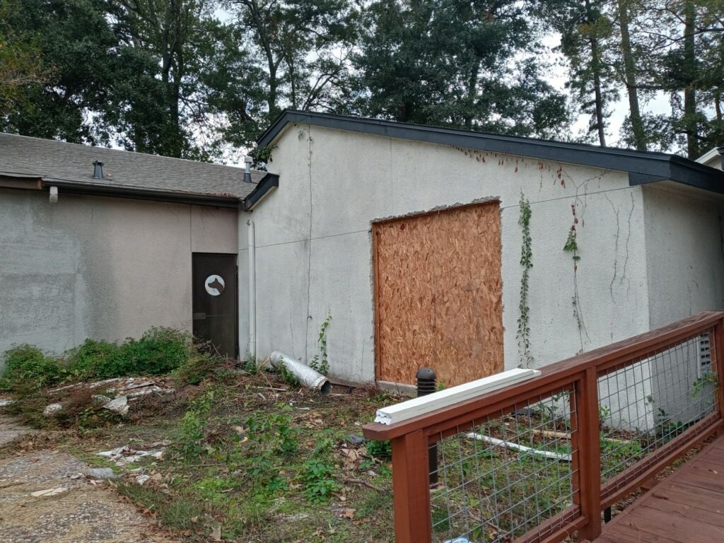 A shed with a wooden door and a fence in front of it.