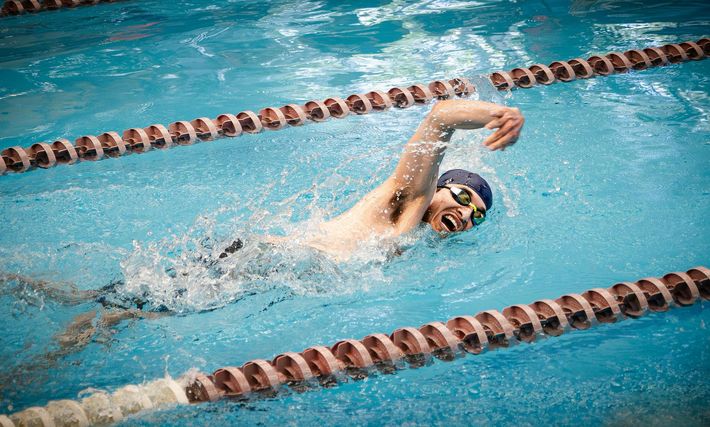 Swimmer doing freestyle in an outdoor pool between lane lines