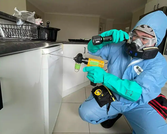 Person in Protective Suit Spraying Insecticide in a Kitchen — NatureWise Pest Control In Port Macquarie, NSW