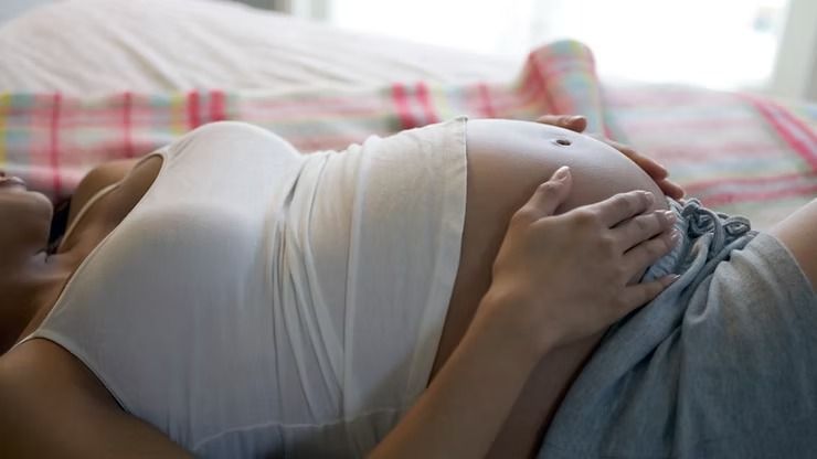 Pregnant Person Resting on a Bed, Hands on Belly — NatureWise Pest Control In Port Macquarie, NSW