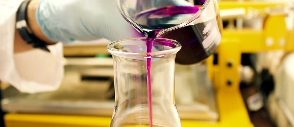 A Person Pouring a Purple Liquid From a Beaker Into a Flask — NatureWise Pest Control In Port Macquarie, NSW