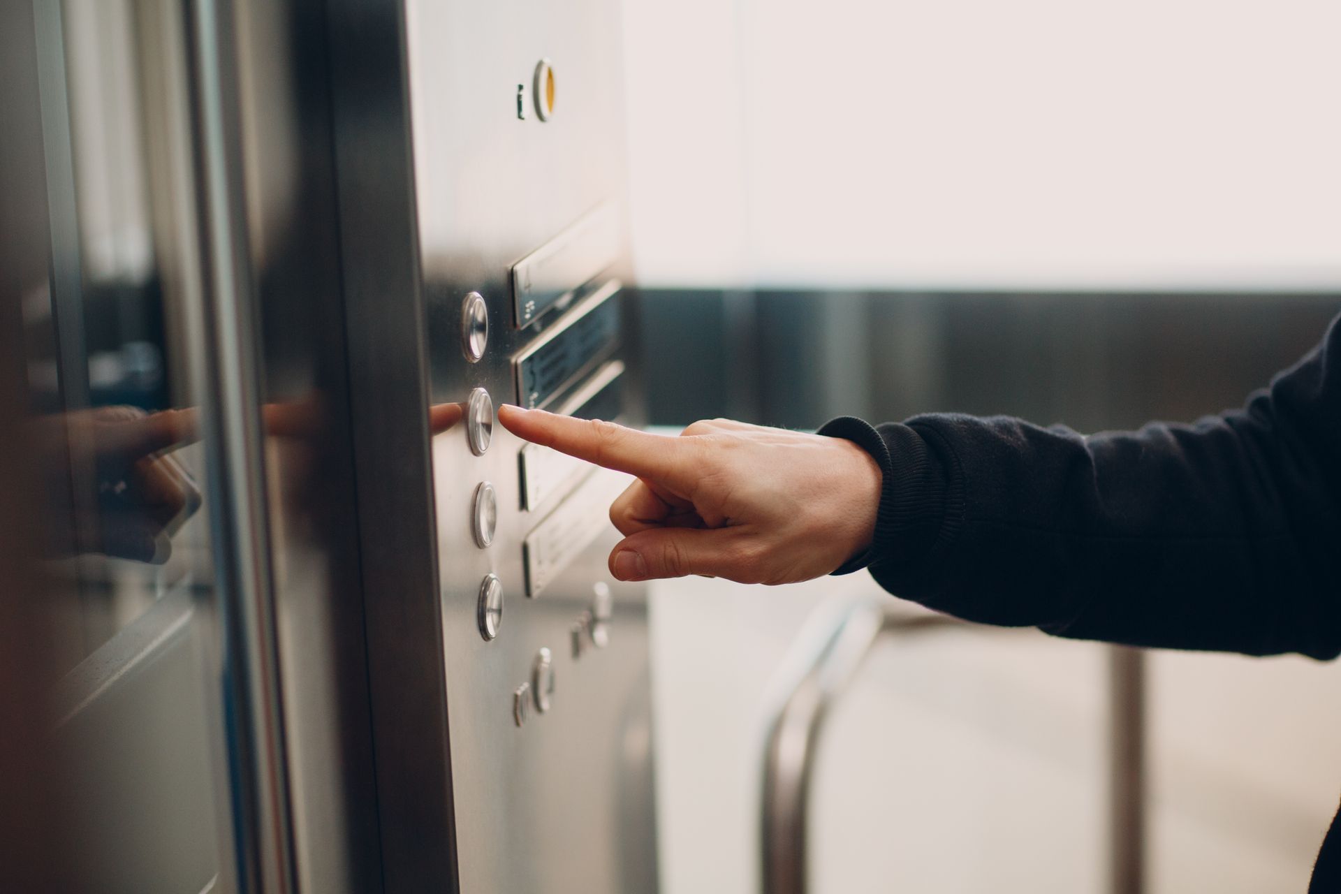 Person's finger pressing a button on a metallic control panel. Person's finger pressing a button on a metallic control panel.