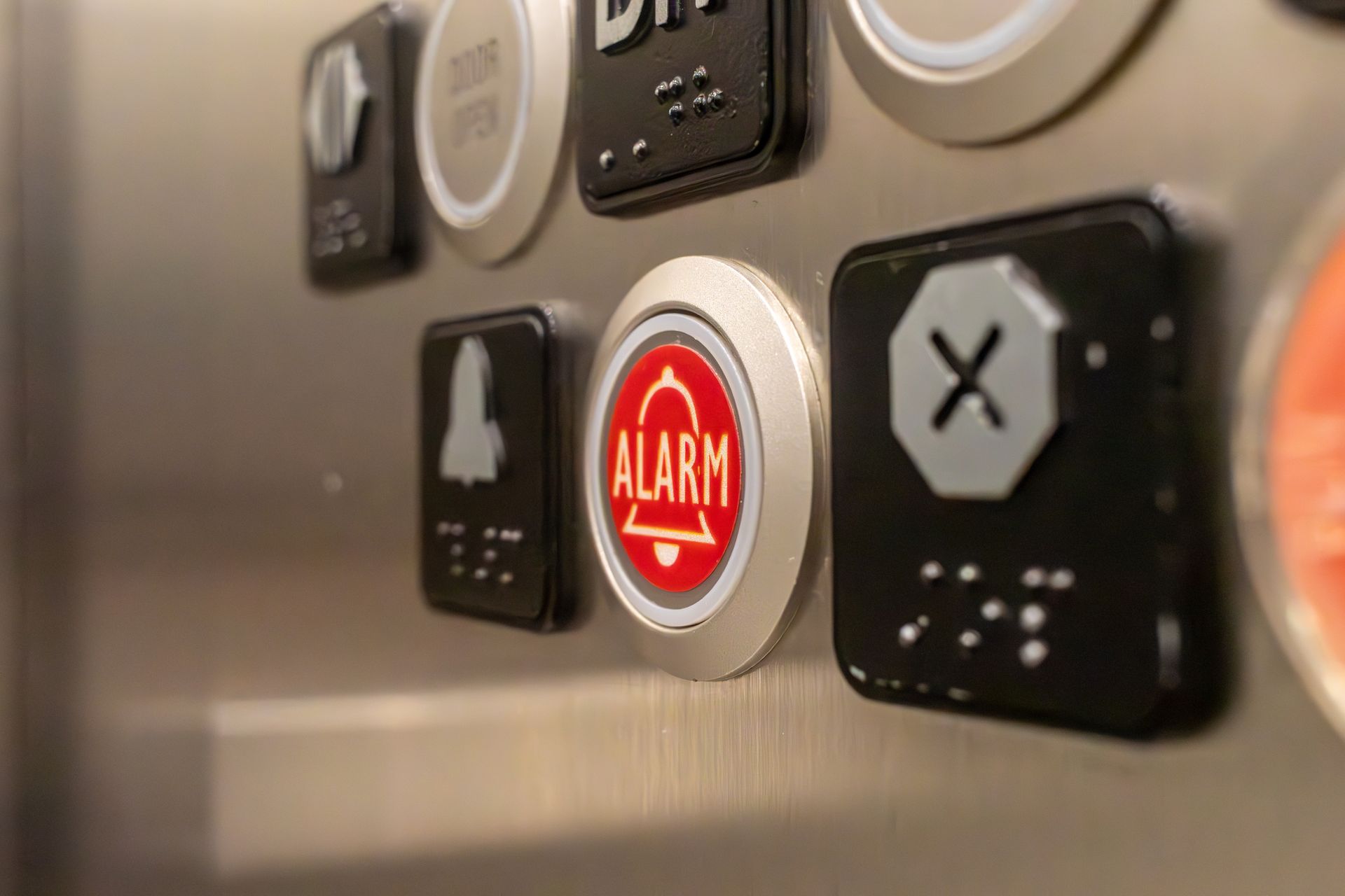 Elevator control panel with buttons, including door open, alarm bell, and a button with an X symbol. Elevator control panel with buttons, including door open, alarm bell, and a button with an X symbol.
