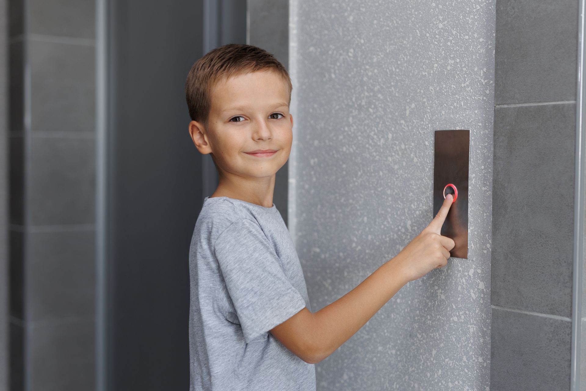 Boy presses elevator button with smiling expression. Boy presses elevator button with smiling expression.
