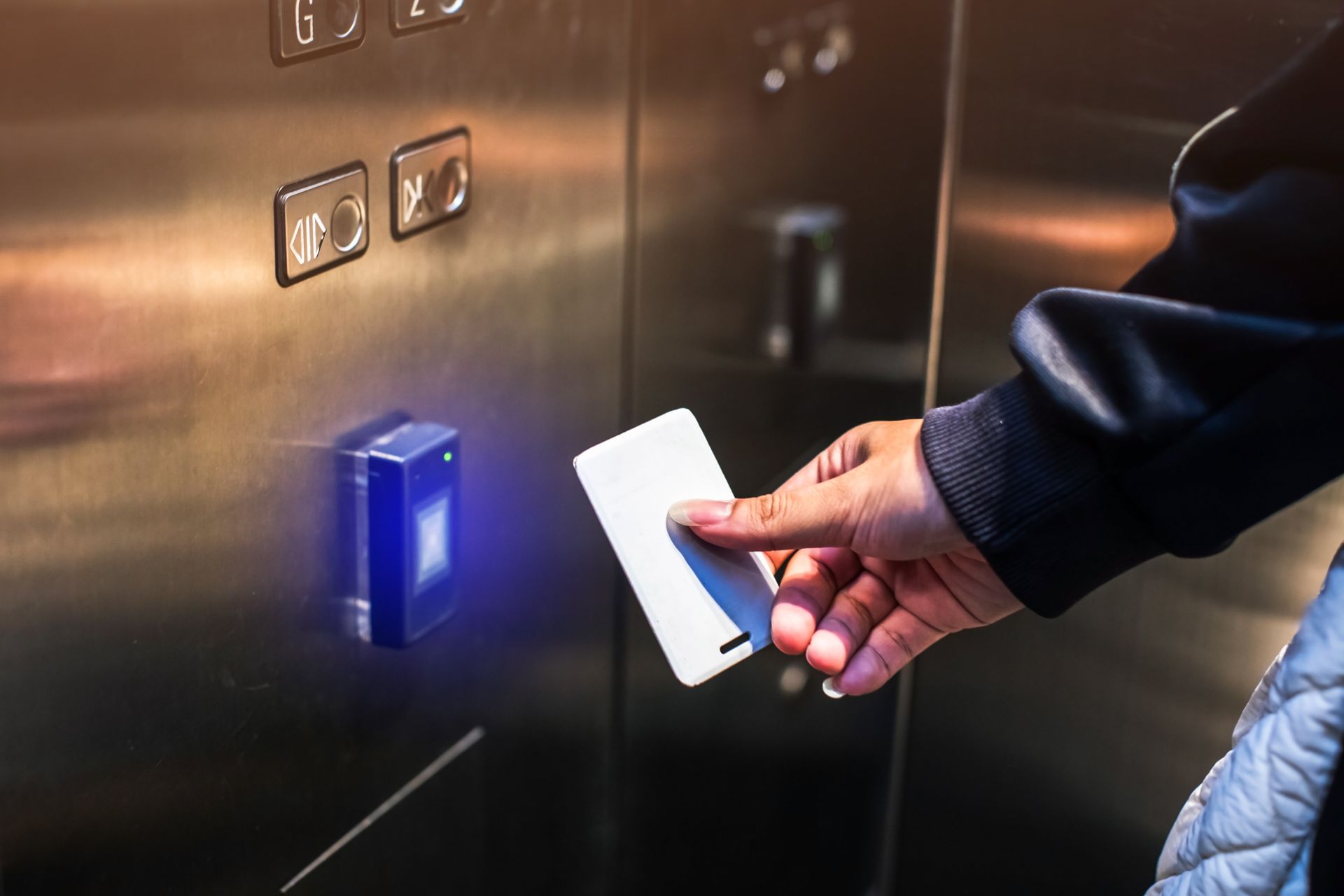 Person uses key card to activate elevator button. Person uses key card to activate elevator button.
