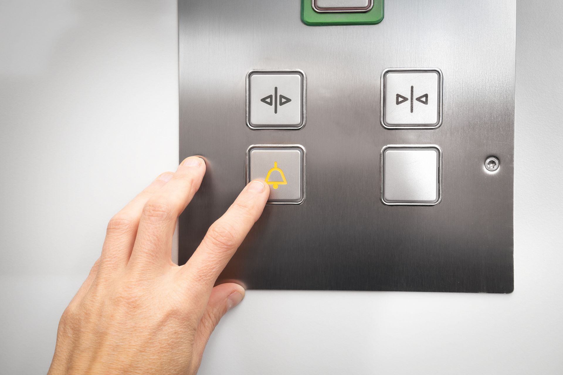 Hand pressing a silver elevator call button with a bell symbol. Hand pressing a silver elevator call button with a bell symbol.