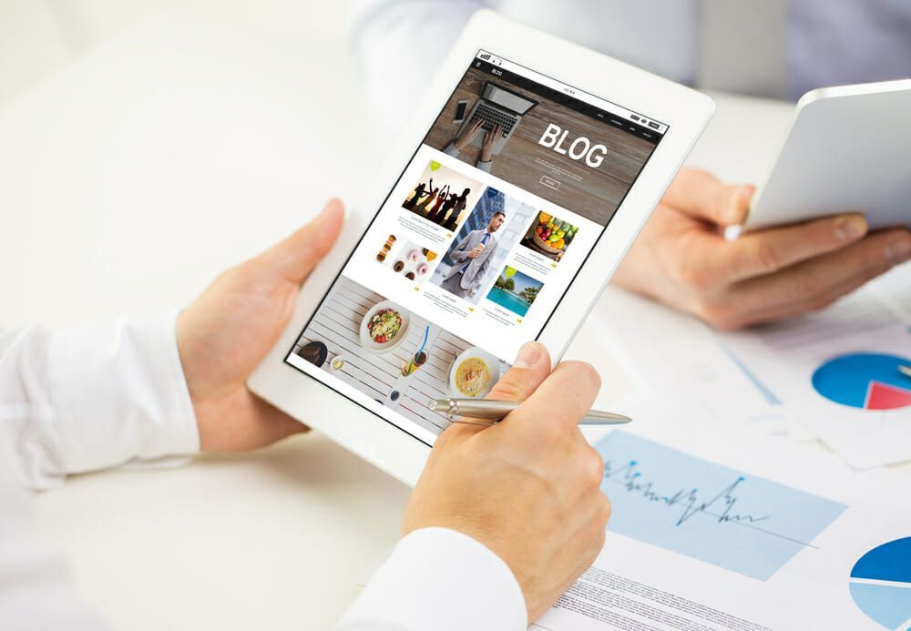 hands holding tablet with blog on it