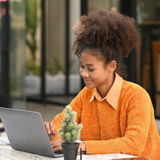 A woman is sitting at a table using a laptop computer.