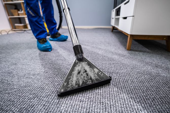 A person is cleaning a carpet with a vacuum cleaner.