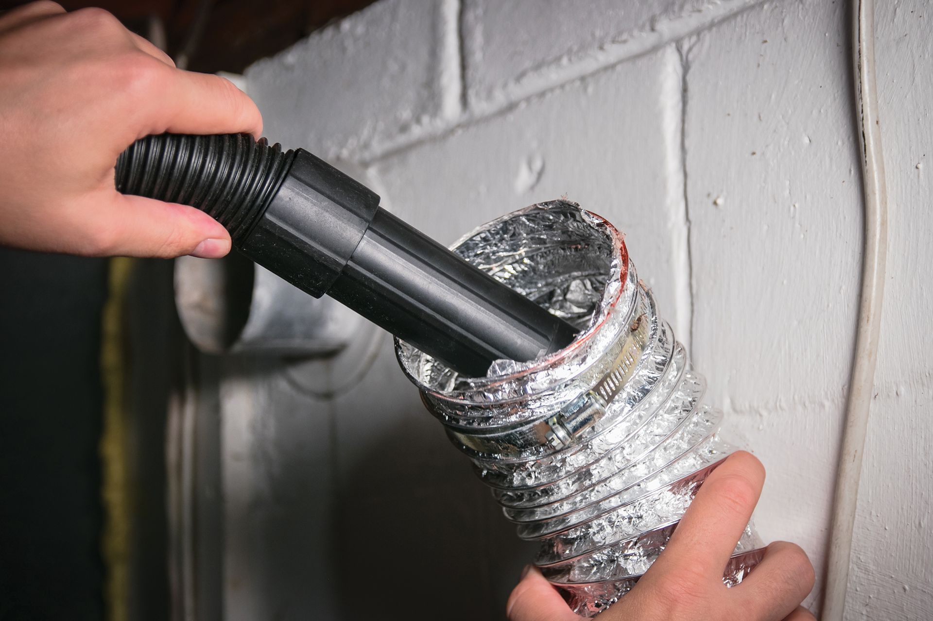 A person is using a vacuum cleaner to clean a duct.