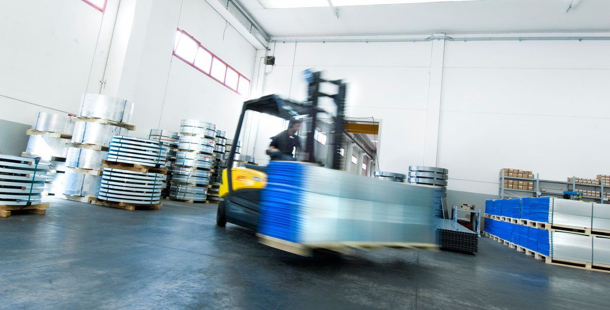 Mulettista che trasporta bancale di paraspigoli per edilizia.