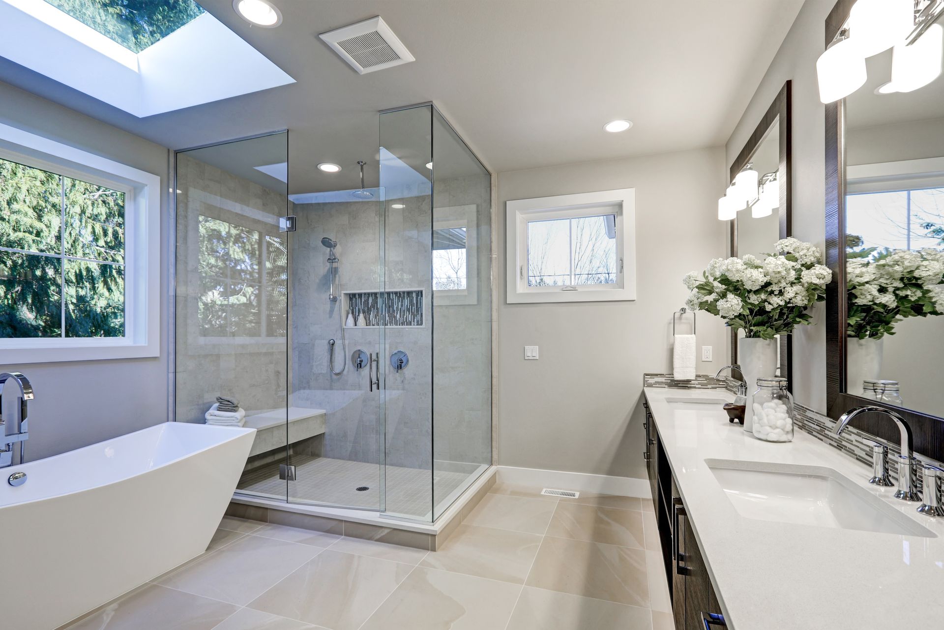 Bright modern bathroom with freestanding tub, glass shower, double vanity, and large windows Bright modern bathroom with freestanding tub, glass shower, double vanity, and large windows