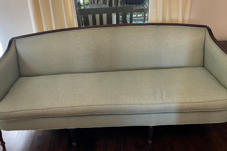 A white couch is sitting on a wooden floor in a living room.