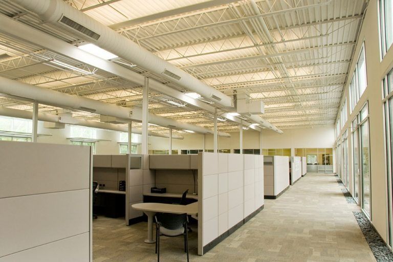 A man wearing a mask is spraying a chair in a living room.