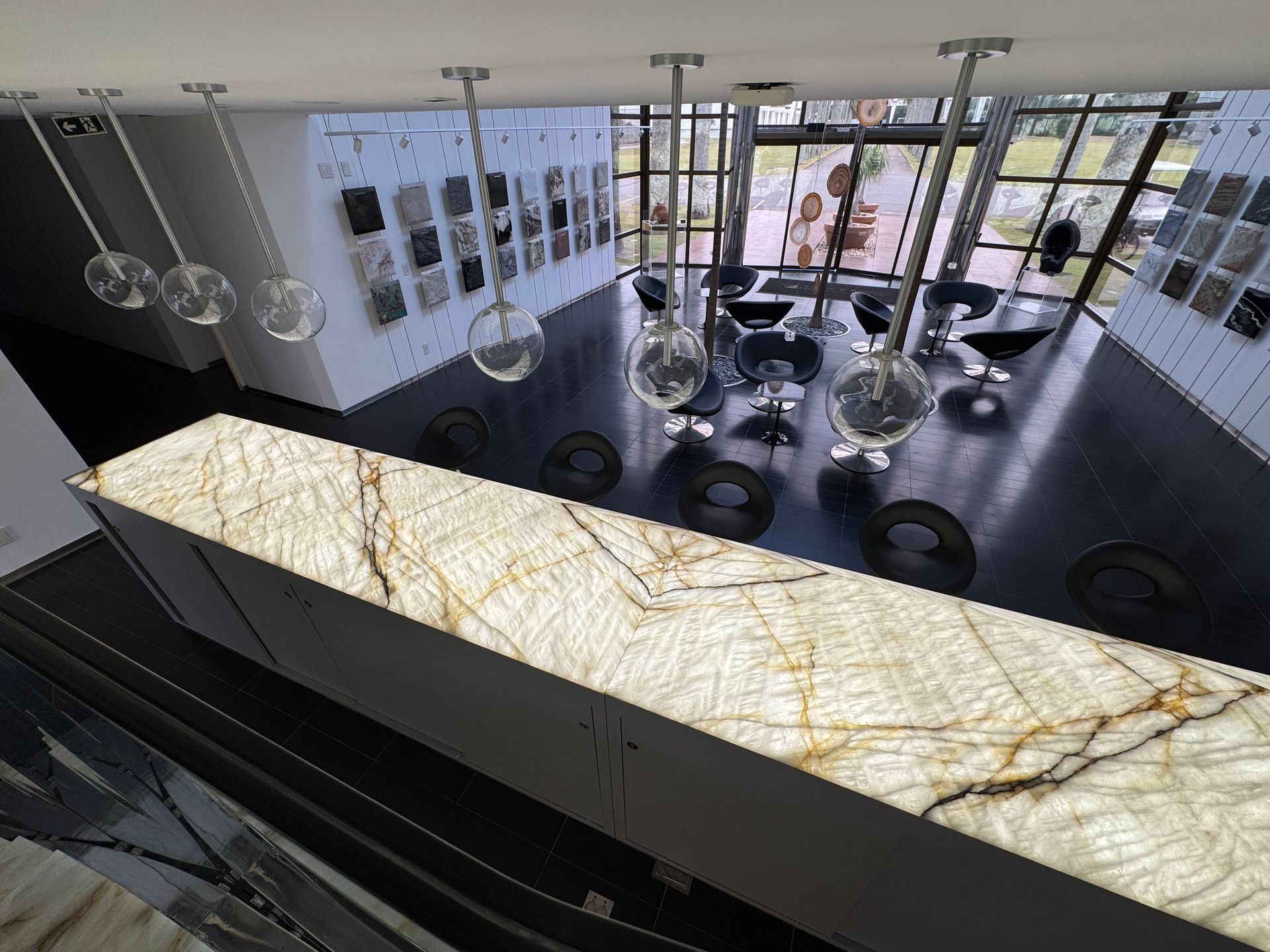 Modern minimalist lobby with marble counter, pendant lights, lounge chairs, and large windows.