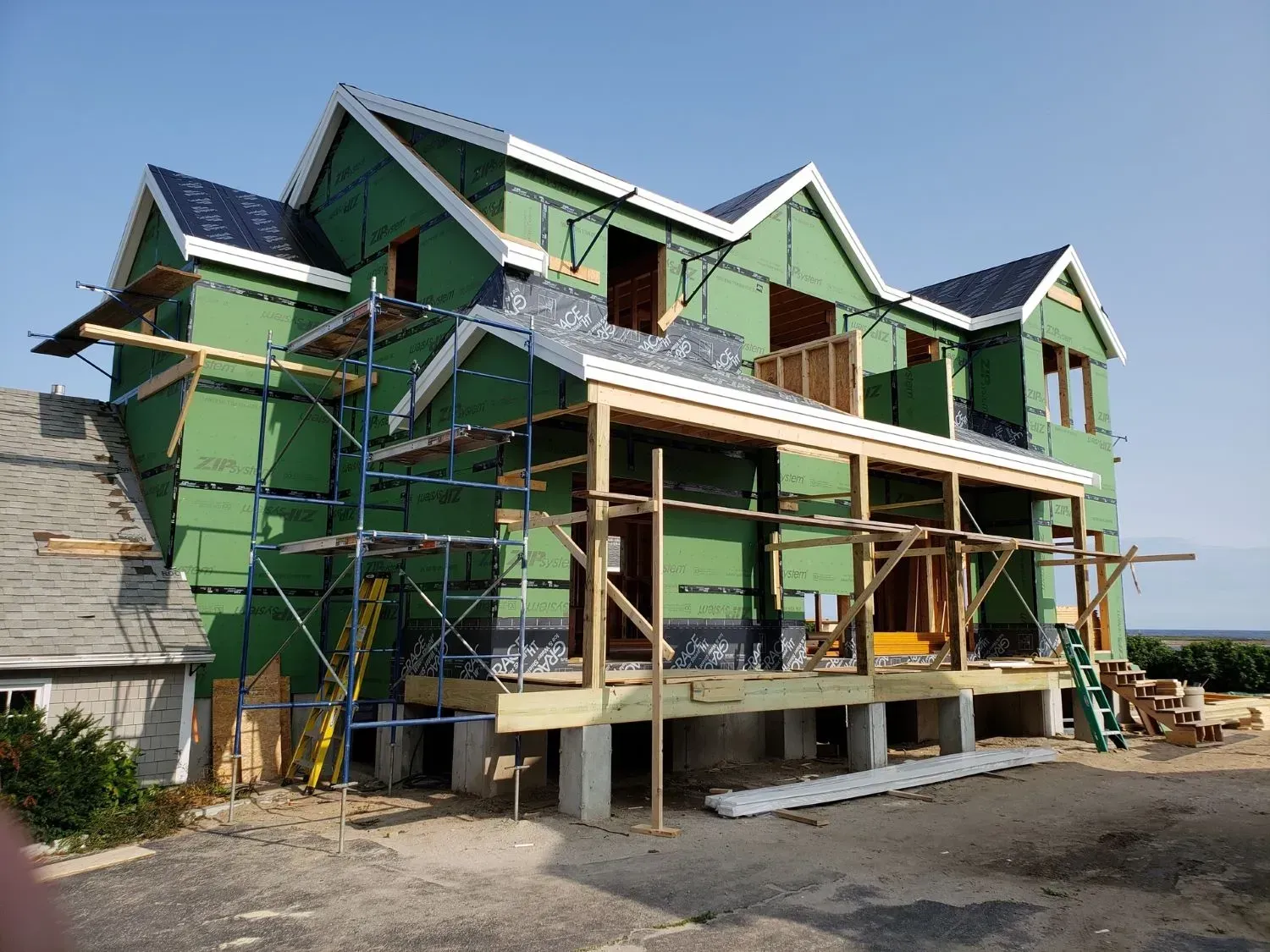 A house under construction with green siding and scaffolding
