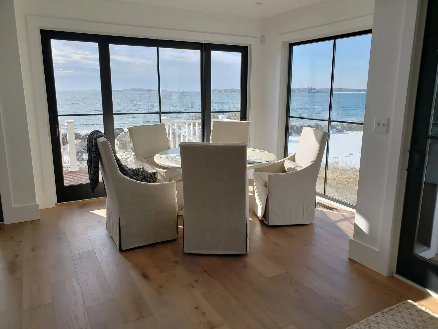 A dining room with a table and chairs and a view of the ocean.