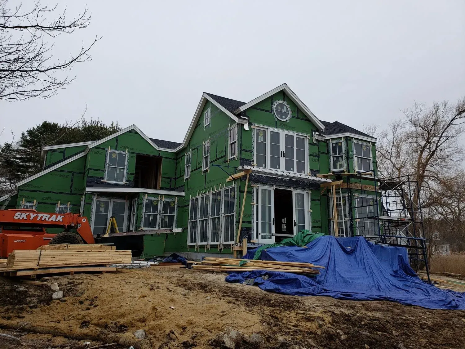 A large green house is being built on top of a dirt hill.