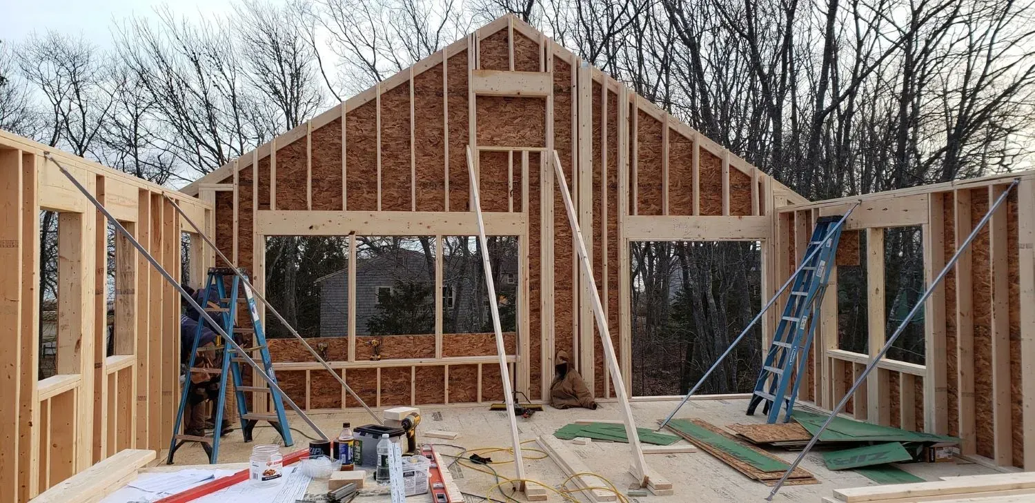 A large wooden house is being built in the woods.