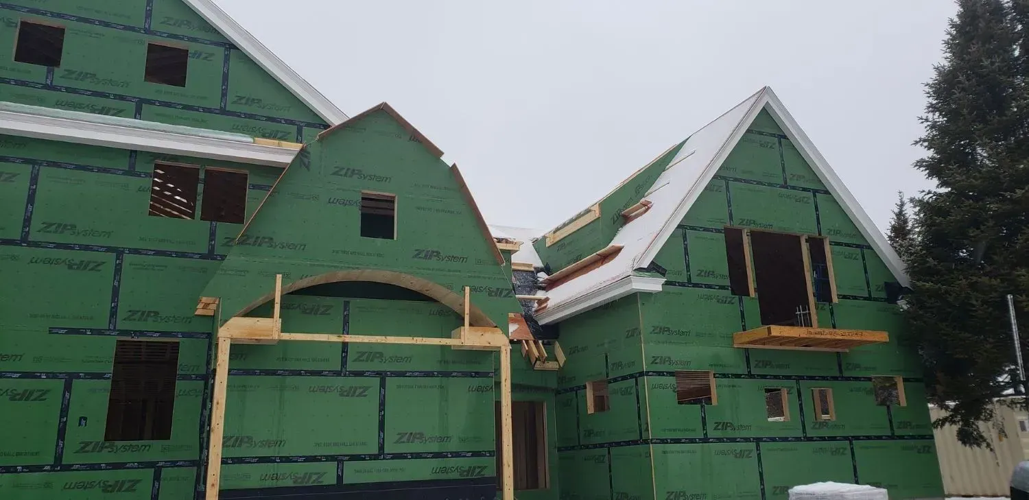 A house is being built with green siding and a white roof.