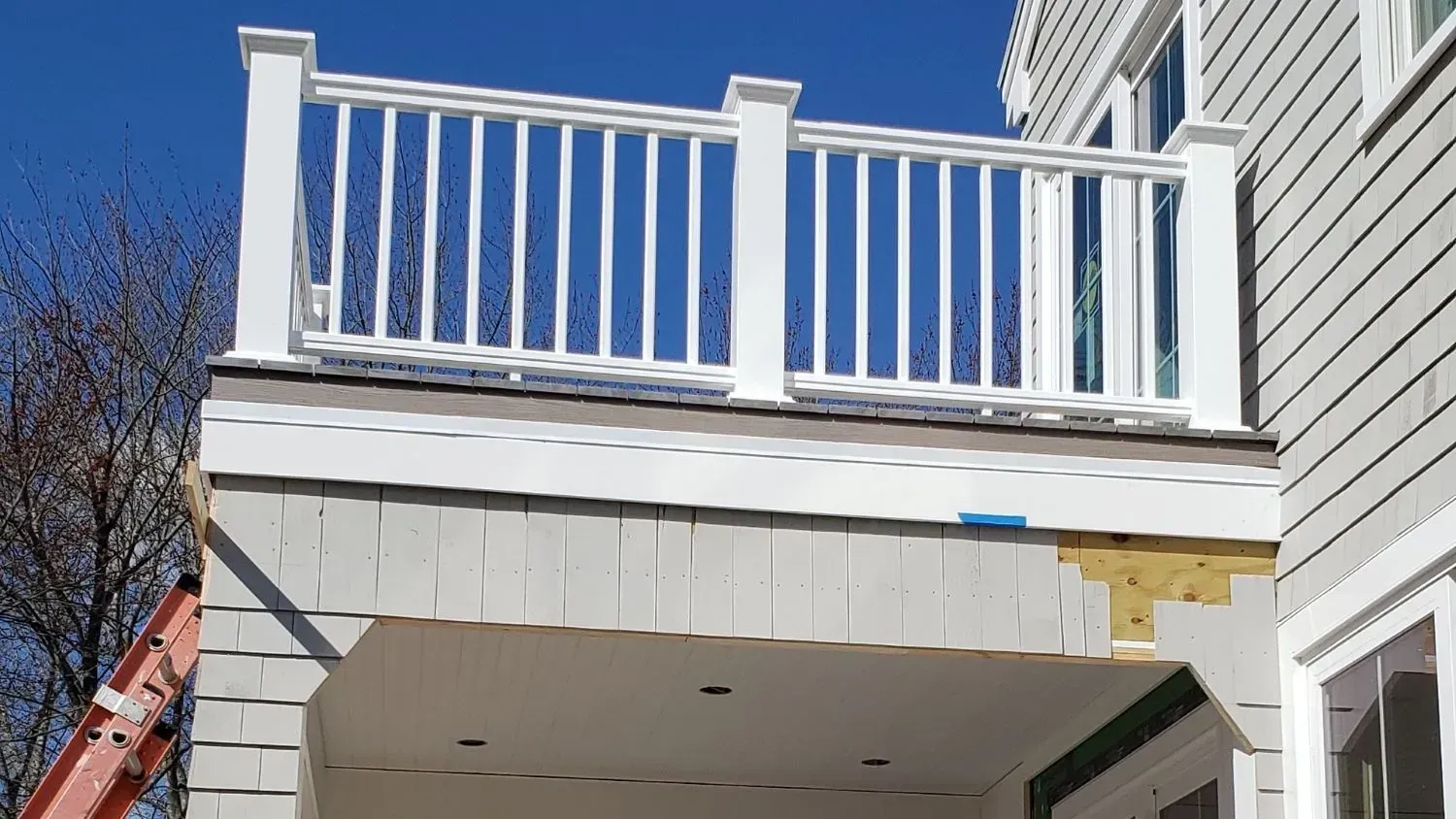 A white deck is being built on the side of a house.