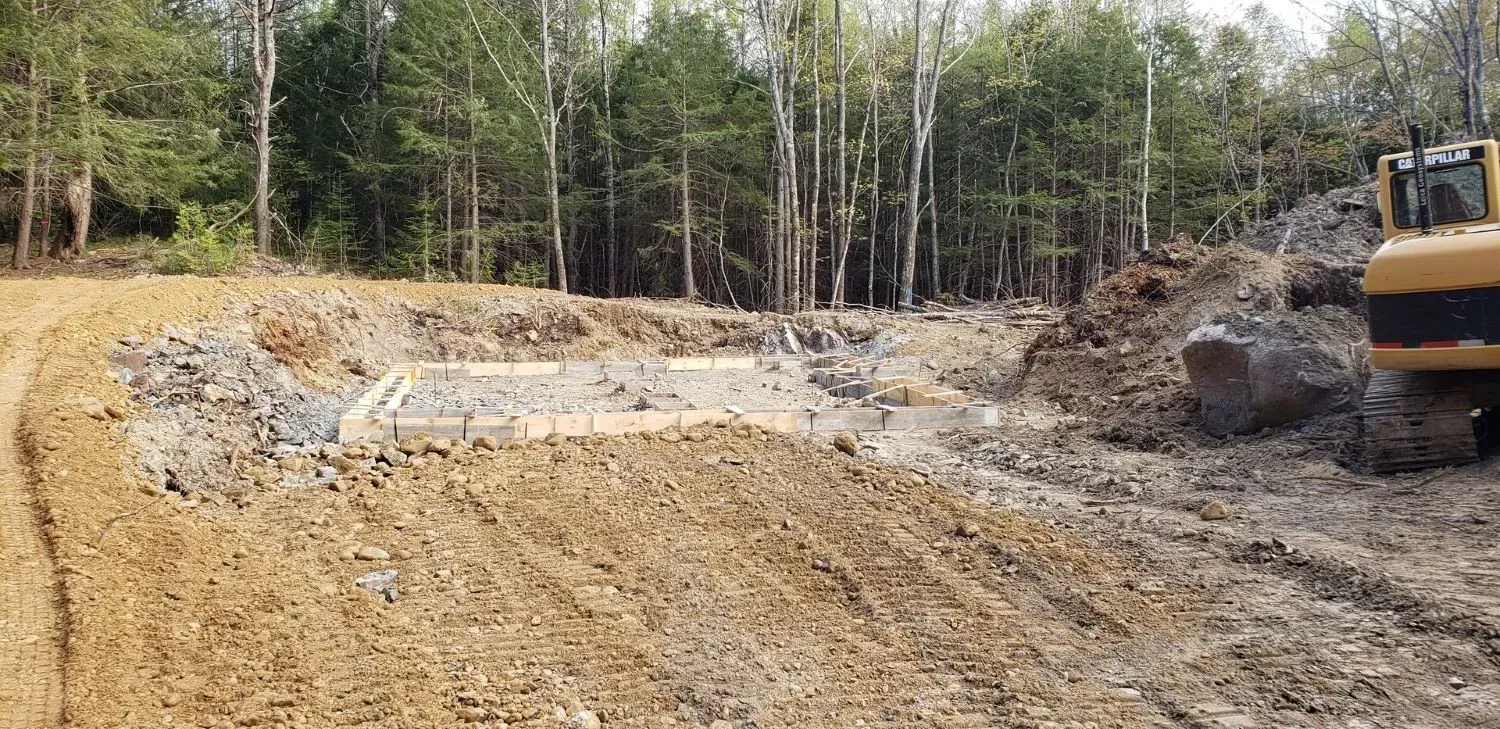A bulldozer is moving dirt in a field with trees in the background.