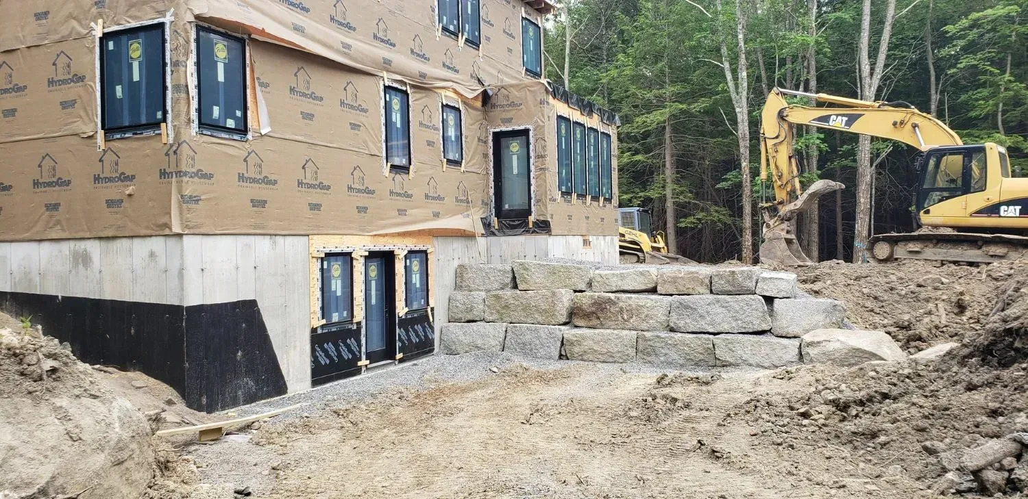 A large house is being built in the middle of a dirt field.
