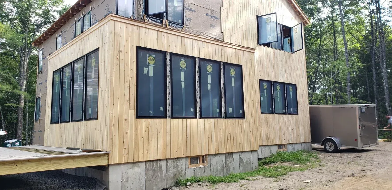 A large wooden house with a lot of windows is being built in the woods.