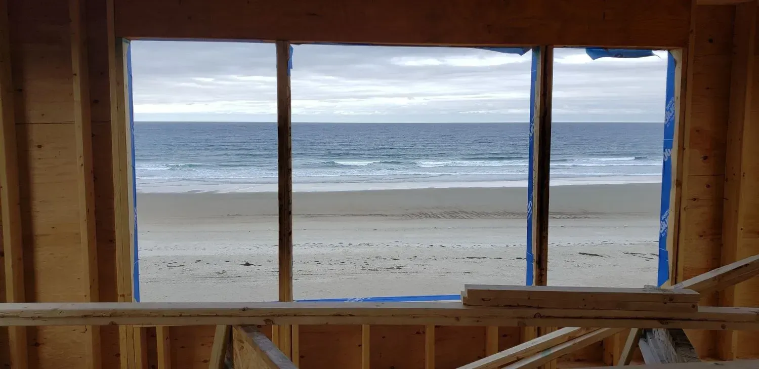 A window with a view of the ocean in a building under construction.
