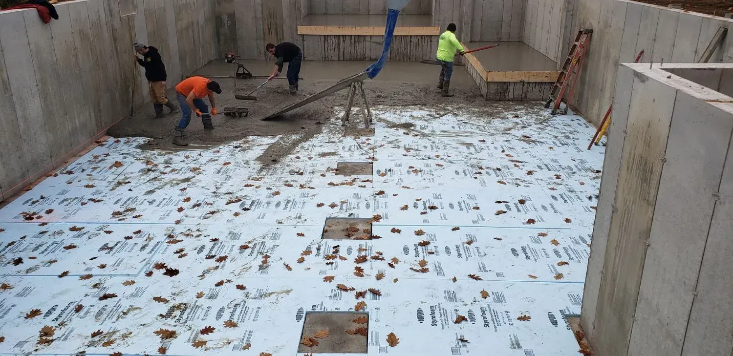 A group of construction workers are working on a concrete floor.