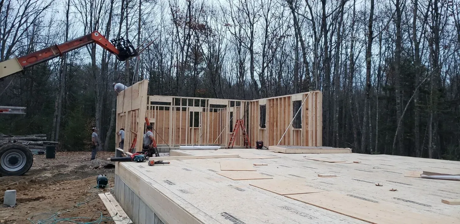A large wooden house is being built in the middle of a forest.