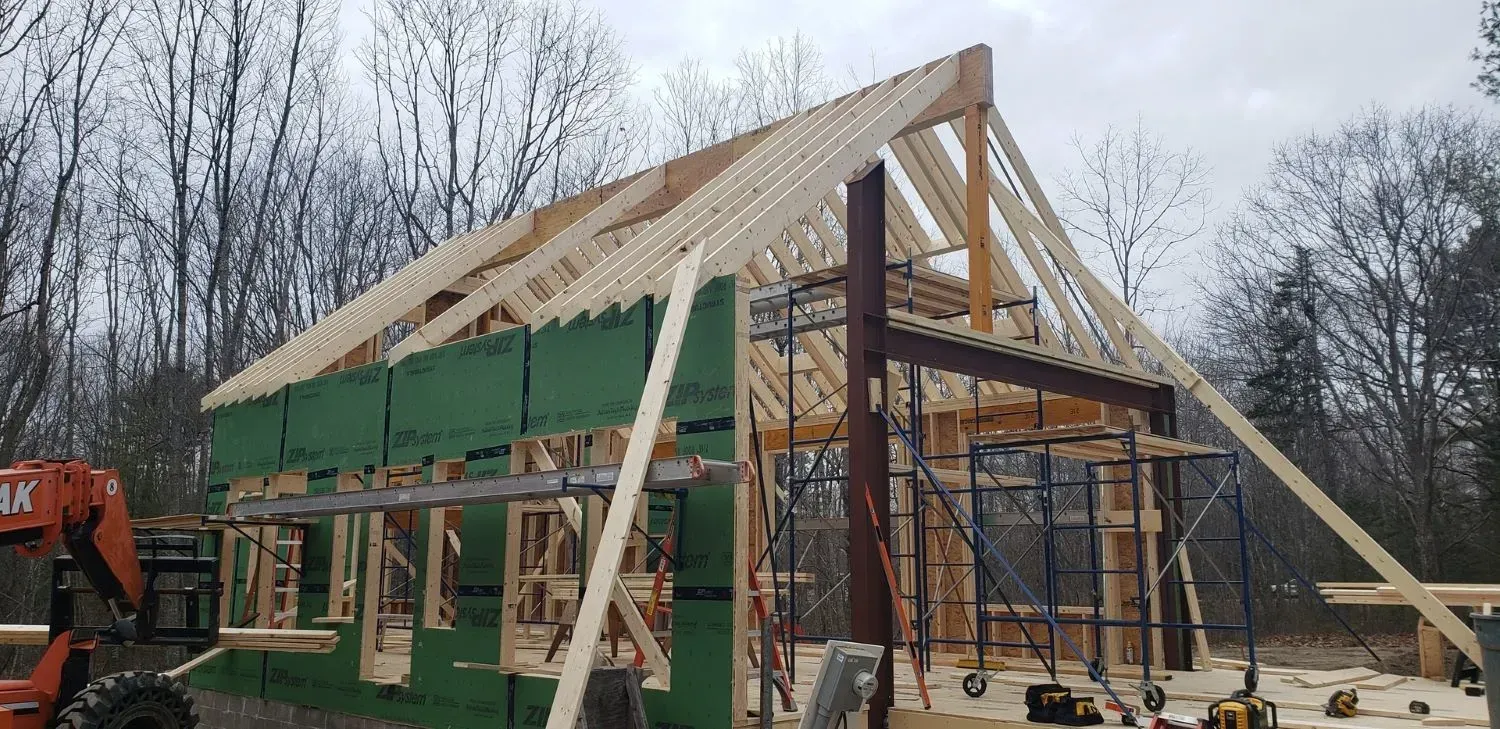 A large wooden structure is being built in the middle of a forest.